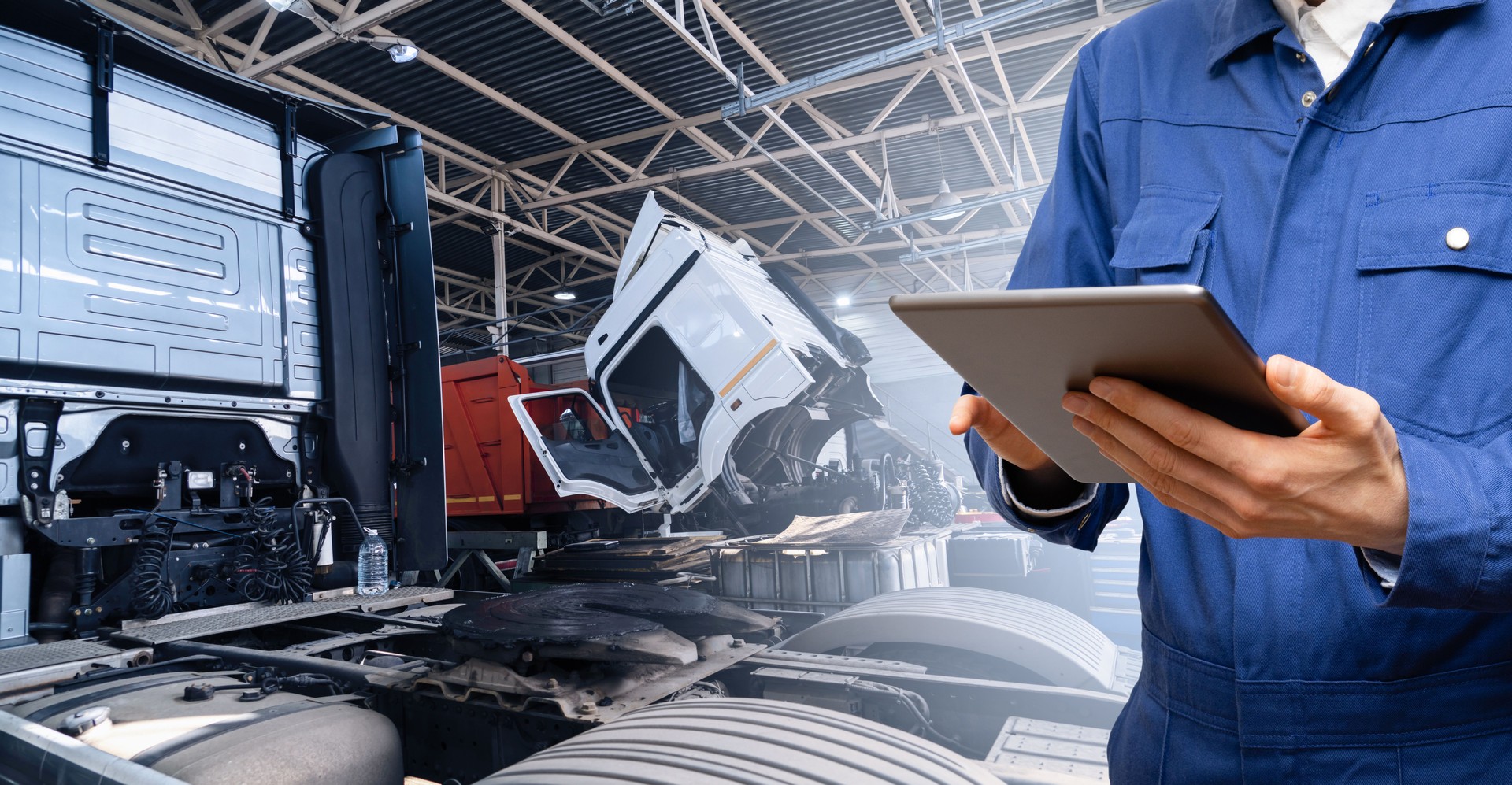 Serviceman with digital tablet on the background of the truck in the garage